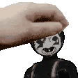 a hand is petting a black and white doll 's head .