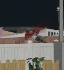 a bird is sitting on top of a white fence next to a building .