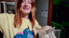 a woman in a yellow shirt is holding a small animal in her arms .