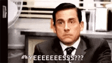 a man in a suit and tie is making a funny face while sitting at a table .