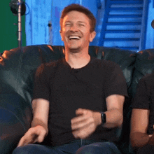 a man is laughing while sitting on a couch