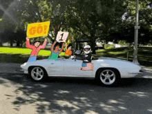 a group of people are riding in a white sports car .