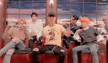 a group of young men are sitting in front of a window .