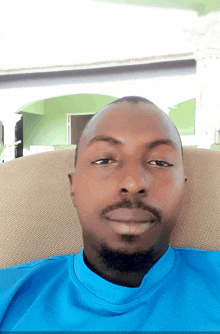a man in a blue shirt sits on a chair