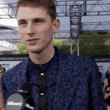 a man in a blue suit is holding a microphone that says billboard