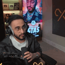a man wearing headphones and glasses is talking into a microphone in front of a sign that says gta5