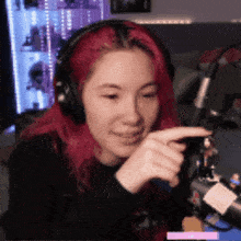 a girl with red hair is wearing headphones and pointing at something .