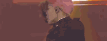 a close up of a person with pink hair wearing a black jacket and ear buds .