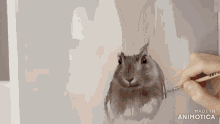 a person is painting a rabbit on a canvas with the words made in animotica visible