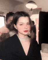 a woman wearing a black top and a diamond necklace looks at the camera