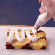 a person frosting a brownie with whipped cream