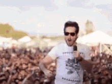 a man is holding a microphone in front of a crowd of people .