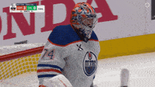 a hockey player with the number 74 on his jersey stands on the ice