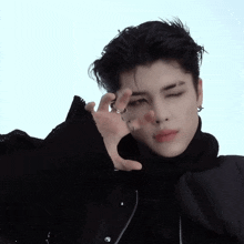 a young man wearing a black jacket and a ring on his finger