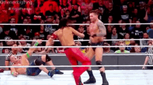a wrestler in a red outfit is kicking another wrestler in the ring .