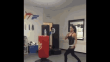 a woman is kicking a punching bag in a gym