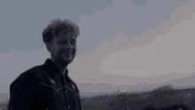 a man with curly hair is wearing ear buds and smiling