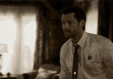 a man in a white shirt and tie has a badge on his chest that says ' b '