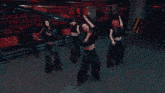 a group of women are dancing in a dark room with red crates in the background