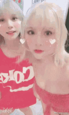 two blonde girls are posing for a picture together .