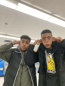 two boys are making funny faces and one is wearing a kach shirt