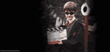 a man in a harry potter costume is holding a clapper board in a dark room .