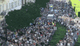 a large crowd of people are gathered on a street in front of a building that says ' kovacs '