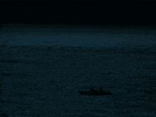 a man in a dark room is holding his hand up