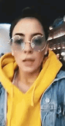 a woman wearing a yellow hoodie and sunglasses