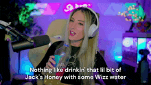 a woman wearing headphones is holding a bottle of water in front of a microphone