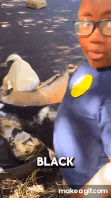 a young boy wearing glasses and a yellow pin is standing next to a bucket of ducks .