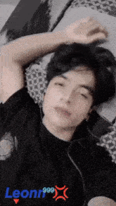 a young man is laying on a bed with the name leonn999 on the bottom right