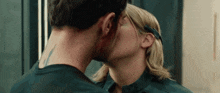a man and a woman are kissing in front of a mirror in a room .