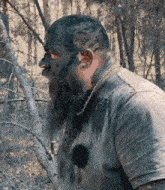 a man with a beard and chain around his neck is covered in mud