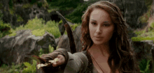 a woman with long hair is holding a bow and arrow in her hand .