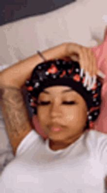 a woman is laying on a bed with her head on a pillow and wearing a hat .