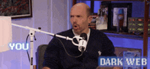 a man sitting in front of a microphone with the words you dark web on the bottom right