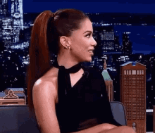 a woman in a black dress is sitting in a chair with her legs crossed .