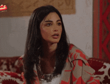 a woman sitting on a couch with arabic writing on the bottom left