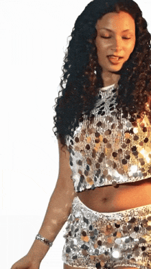 a woman with curly hair is wearing a crop top and shorts with sequins on them
