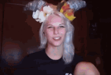 a woman wearing a crown of flowers on her head is smiling .