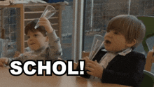 two young boys are playing with a beaker and the word schol is on the table in front of them