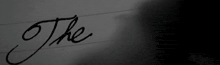 a person is writing the word the on a piece of paper in black and white .
