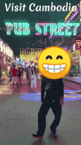 a man walking down a street with a smiley face in front of his head and the words visit cambodia pub street