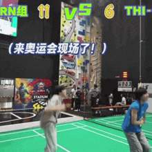 a group of people are playing a game of badminton on a green court with chinese writing on it