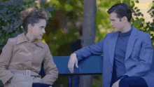 a man and a woman are sitting on a bench and talking to each other
