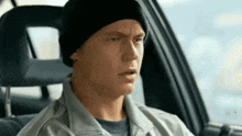 a man wearing a beanie is sitting in a car .