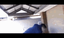 a man in a blue shirt is standing under a roof .