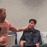 a man wearing an american flag t-shirt is putting his hand on another man 's face