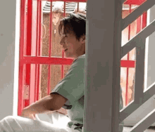 a man is sitting on a staircase next to a red door and smiling .